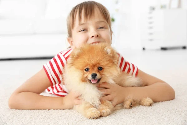 Nettes Mädchen mit kleinem Hund auf dem Boden zu Hause — Stockfoto