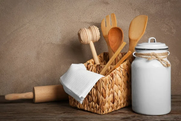 Kitchen utensils in wicker basket and milk churn — Stock Photo, Image