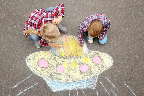 Kleine Kinder malen Alien-Raumschiff mit Kreide auf Asphalt — Stockfoto