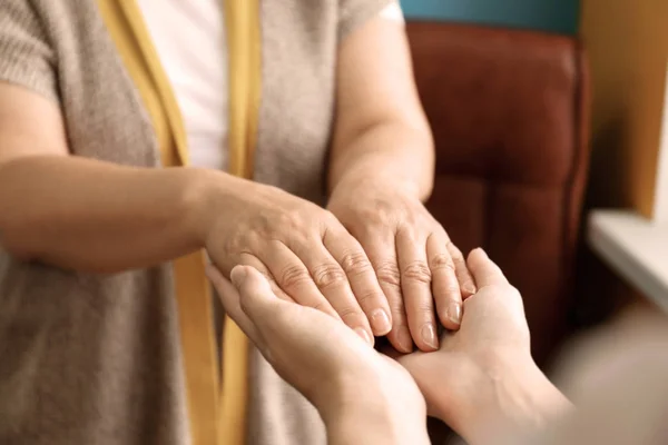 Young woman holding hands of her mother, closeup. Concept of care and support — Stock Photo, Image