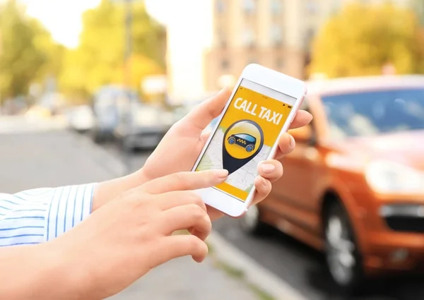 Жінка використовує додаток на мобільний телефон, щоб викликати таксі — стокове фото