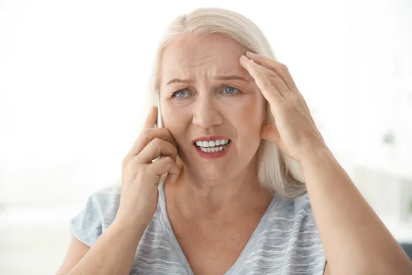 Senior woman speaking on cell phone at home — Stock Photo, Image