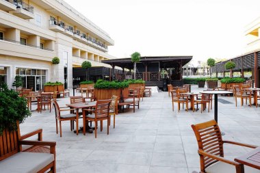 Sandalyeleri ve masaları olan açık hava kafesi.