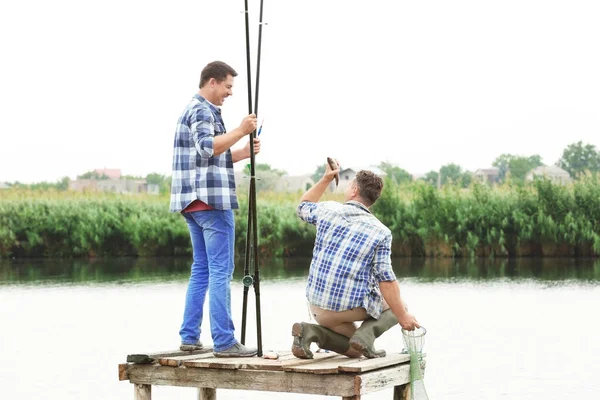 Két ember halászik a mólóról a folyón. — Stock Fotó
