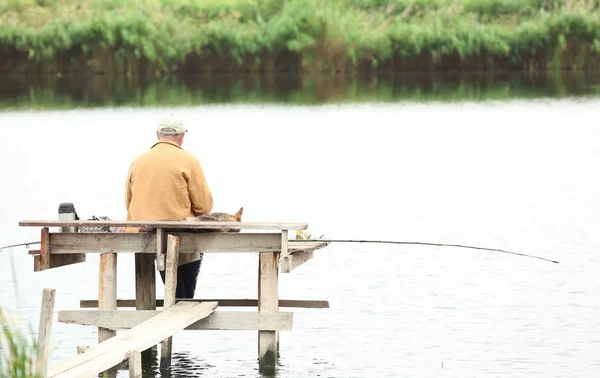 Hombre pescando desde el muelle en el río — Foto de Stock