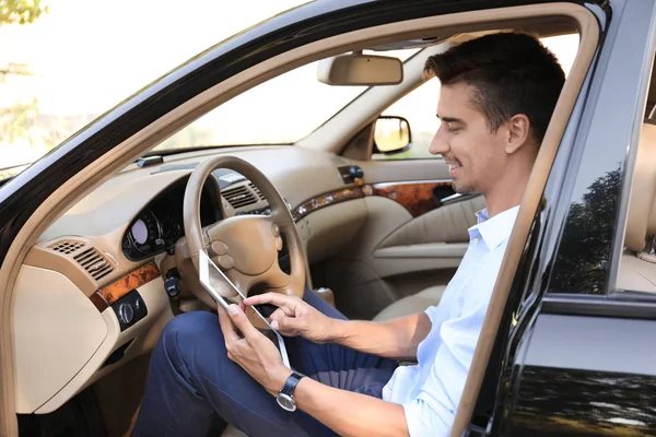 Jovem empresário usando tablet no carro — Fotografia de Stock