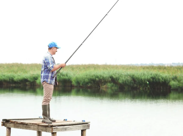 Hombre pescando desde el muelle en el río — Foto de Stock