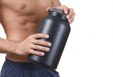 Protein tozu ile siyah kavanoz tutan gömleksiz genç adam 