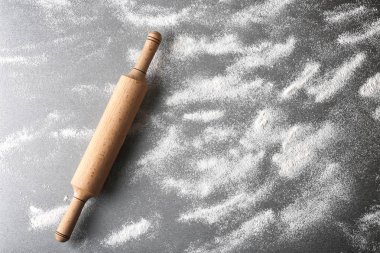 Dağınık un ve gri arka plan üzerinde oklava