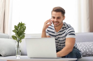 Onun laptop ve cep telefonu kullanan genç yakışıklı adam 