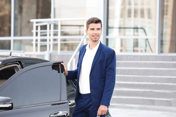 Молодой бизнесмен стоит рядом с машиной — стоковое фото