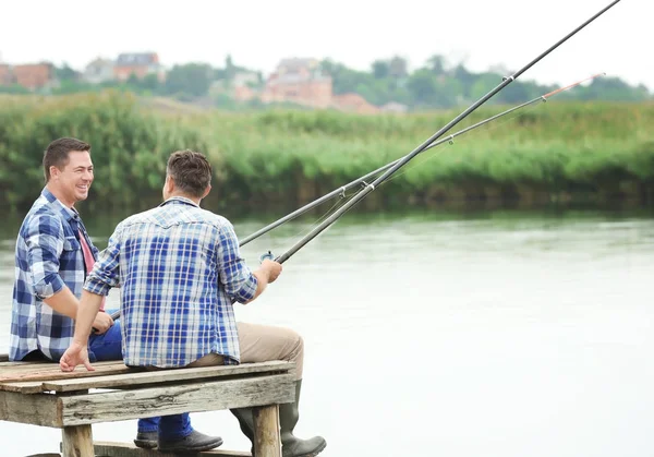 Two men fishing from pier on river — Stock Photo, Image