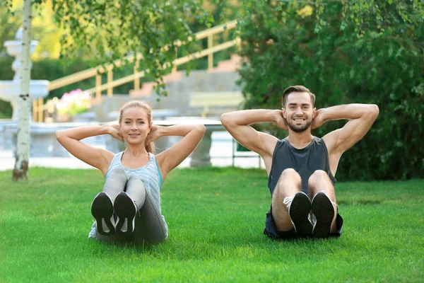 Joven hombre y mujer haciendo ejercicios en el parque — Foto de Stock