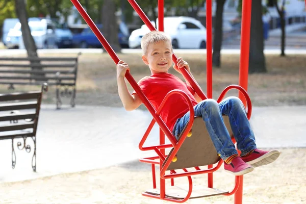 Adorable little boy on swing at playground — Stock Photo, Image