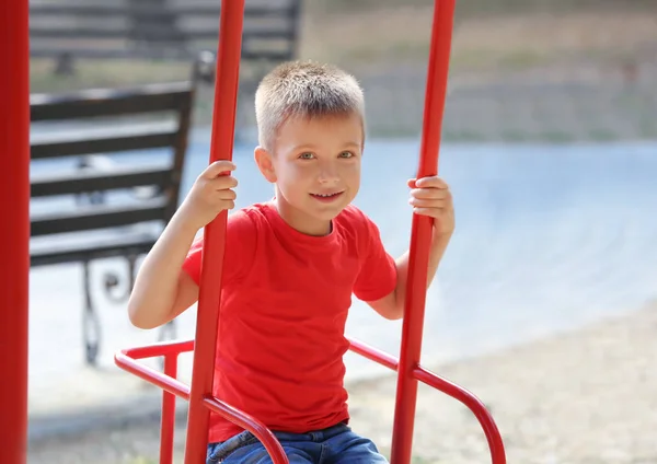 Adorable niño en columpio en el patio de recreo —  Fotos de Stock