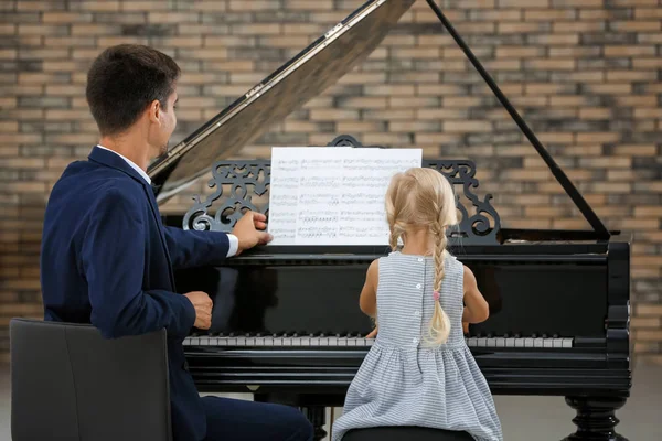 Petite fille et jeune homme jouant du piano — Photo