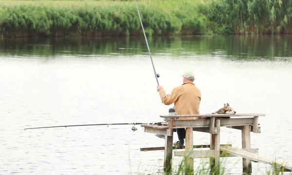 Hombre pescando desde el muelle en el río — Foto de Stock