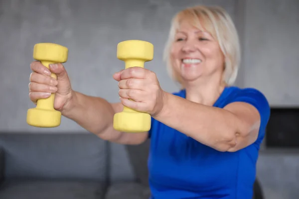 Rijpe vrouw met halters thuis training — Stockfoto