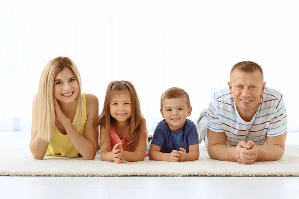 Feliz família deitada no tapete em uma nova casa — Fotografia de Stock