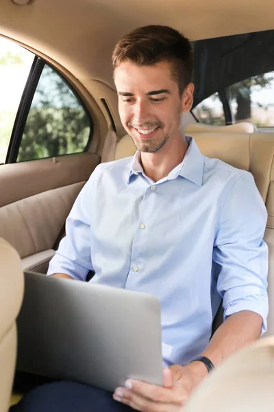 Jovem empresário usando laptop em um carro — Fotografia de Stock