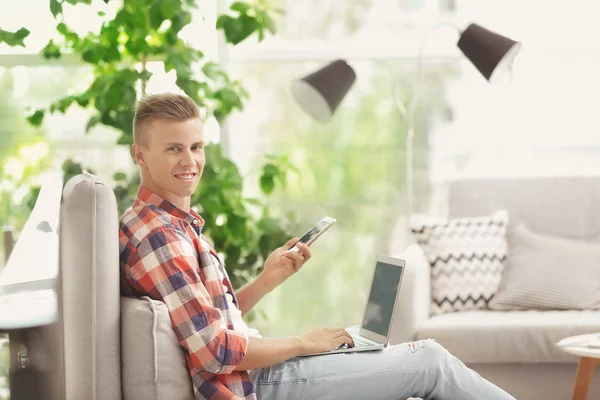 Junger Mann mit Laptop und Handy — Stockfoto
