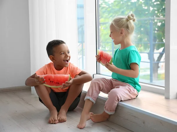 Cute kids eten watermeloen in de buurt van venster thuis — Stockfoto