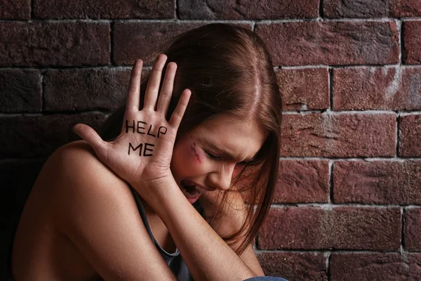Mujer joven maltratada con palabras escritas "Ayúdame" en la palma de la mano —  Fotos de Stock