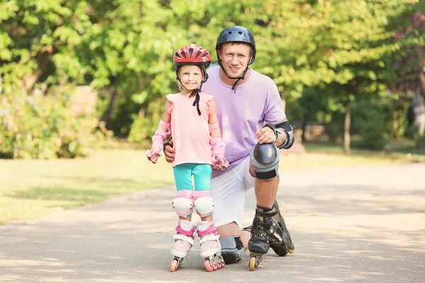 Father with daughter on roller skates in summer park — Stock Photo, Image