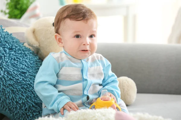 自宅のソファの上に座って水のボトルとかわいい赤ちゃん — ストック写真