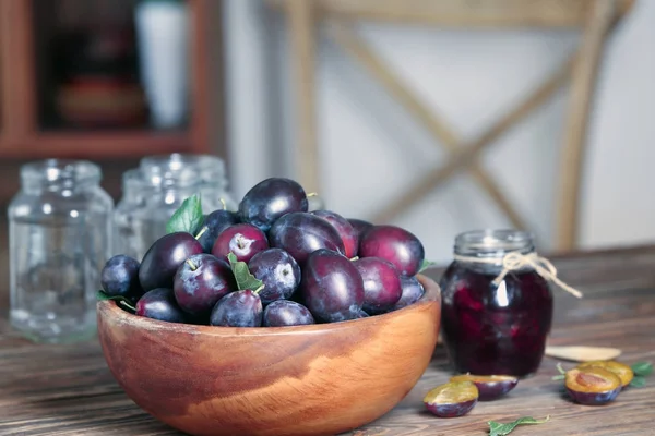 Schaal met pruimen en jar — Stockfoto