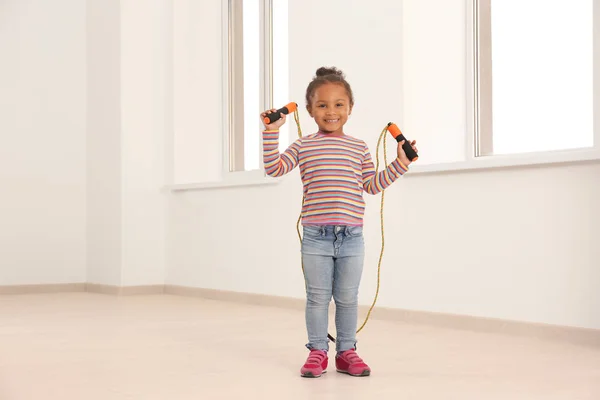 Menina afro-americana bonito pulando corda na sala de luz — Fotografia de Stock