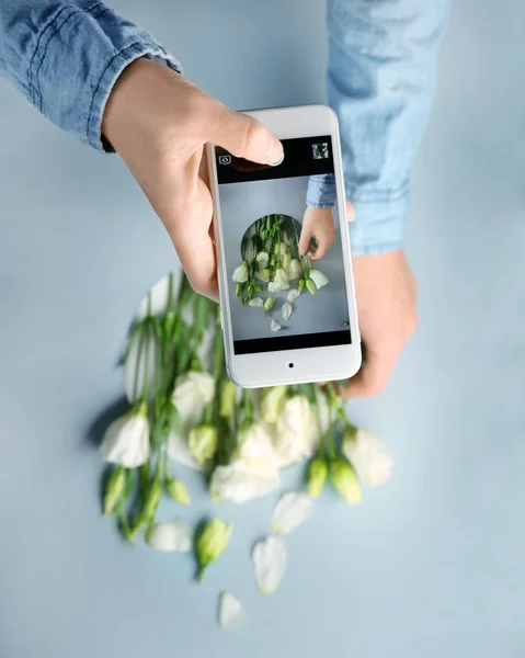 Blogger taking photo of eustoma flowers with cell phone — Stock Photo, Image