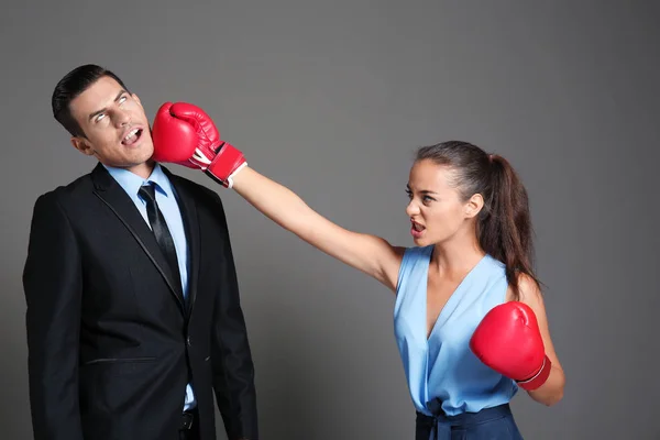 Mujer en guantes de boxeo golpeando hombre de negocios — Foto de Stock