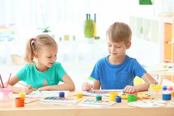 Słodkie dzieci malowanie zdjęcia przy stole w pomieszczeniu — Zdjęcie stockowe