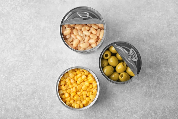 Open tin cans with different food on table — Stock Photo, Image