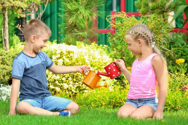 Lindos niños regando plantas en el jardín — Foto de Stock