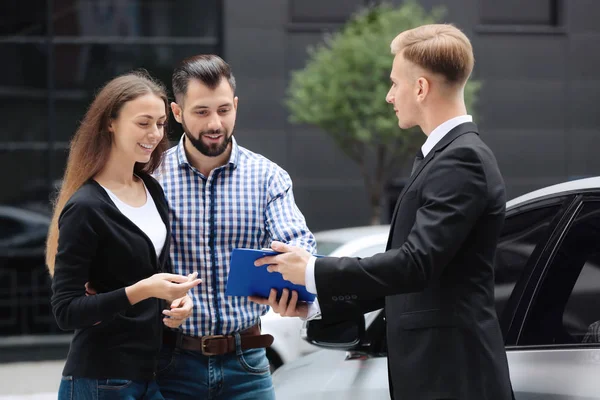Unga par med bil återförsäljare utomhus — Stockfoto
