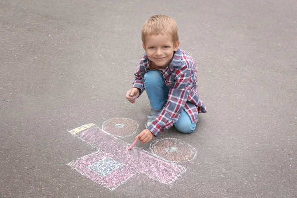 Liten pojke ritning bil med krita på asfalt — Stockfoto