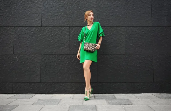Hermosa mujer en vestido verde cerca de la pared al aire libre — Foto de Stock