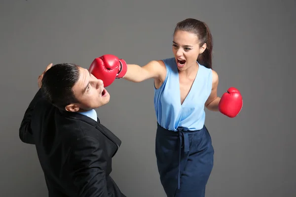 Woman in boxing gloves hitting businessman