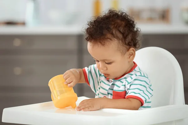 Lindo bebé con botella de agua sentado en la cocina — Foto de Stock