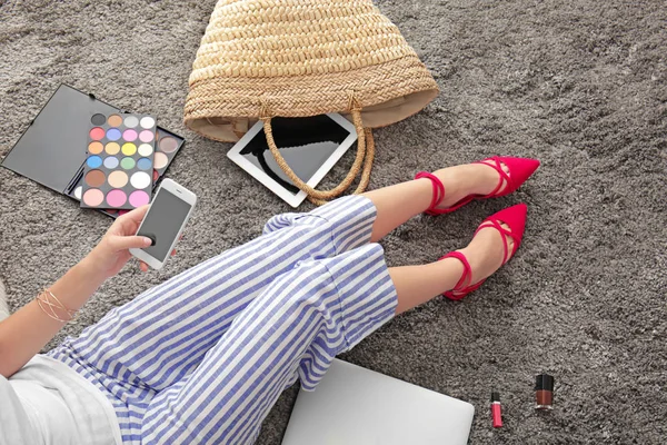 Junge Beauty-Bloggerin benutzt Handy während sie auf dem Boden sitzt — Stockfoto