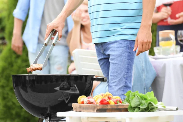 Mann som lager smakfulle biffer på grill, utendørs – stockfoto