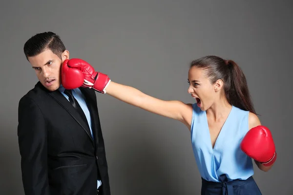 Woman in boxing gloves hitting businessman — Stock Photo, Image