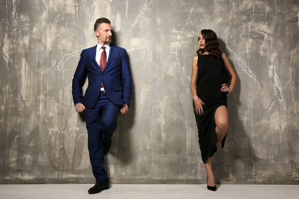 Atraktivní pár v formální oblečení šedé zdi — Stock fotografie