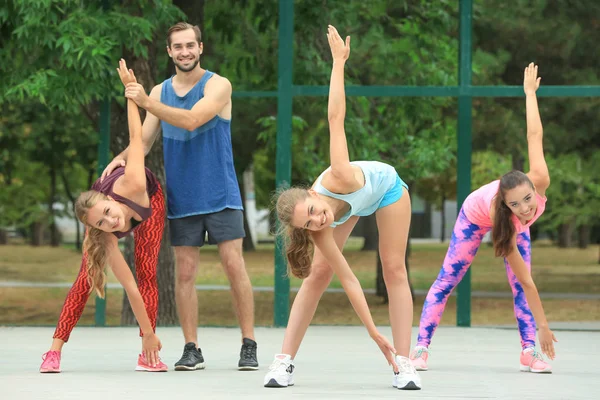 Beautiful young women with trainer exercising in park — Stock Photo, Image