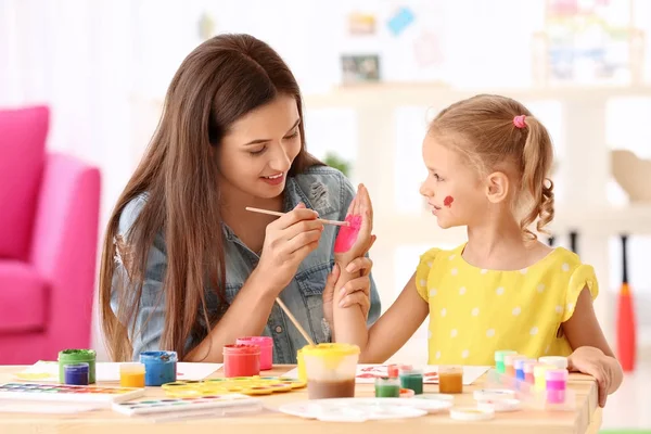 Χαριτωμένο κορίτσι με μητέρα ζωγραφική στο τραπέζι σε εσωτερικούς χώρους — Φωτογραφία Αρχείου