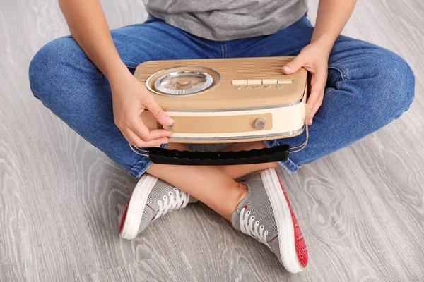 Young woman with retro radio sitting on floor indoors — Stock Photo, Image