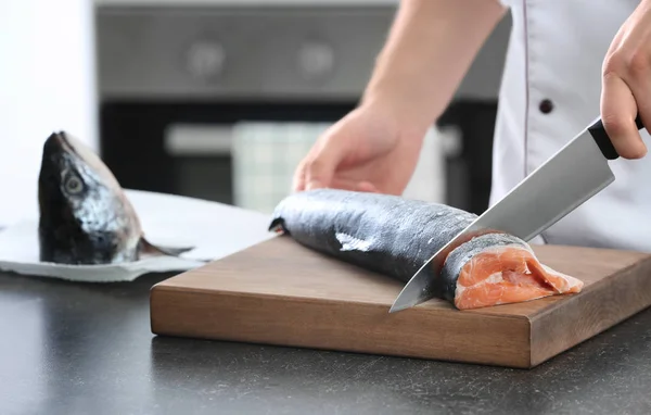 Kocken skär färsk lax i köket — Stockfoto