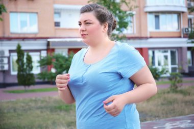 Overweight woman running, outdoors clipart